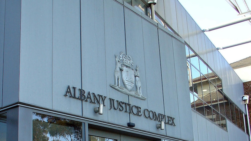 Front entrance to Albany justice complex showing doors, court sign and emblem