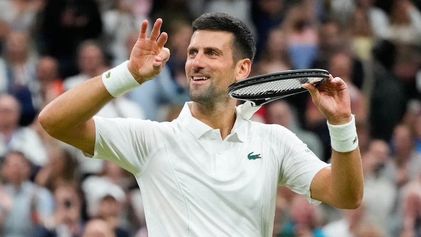 Novak Djokovic smiles and holds his hands up