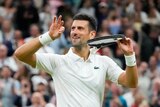 Novak Djokovic smiles and holds his hands up