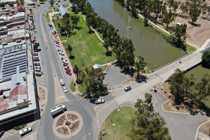 drone shot of a country town with a lake, shops and a few cars parked