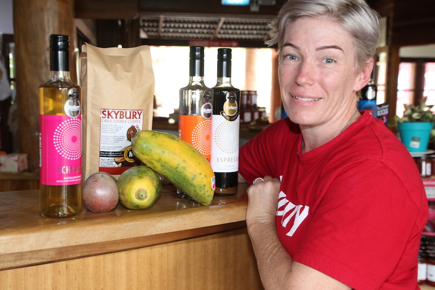 Candy MacLaughlin General Manager of Skybury Coffee standing besides samples of her fruit and spirits 