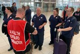 A group of nurses wearing navy scrubs stand in an airport