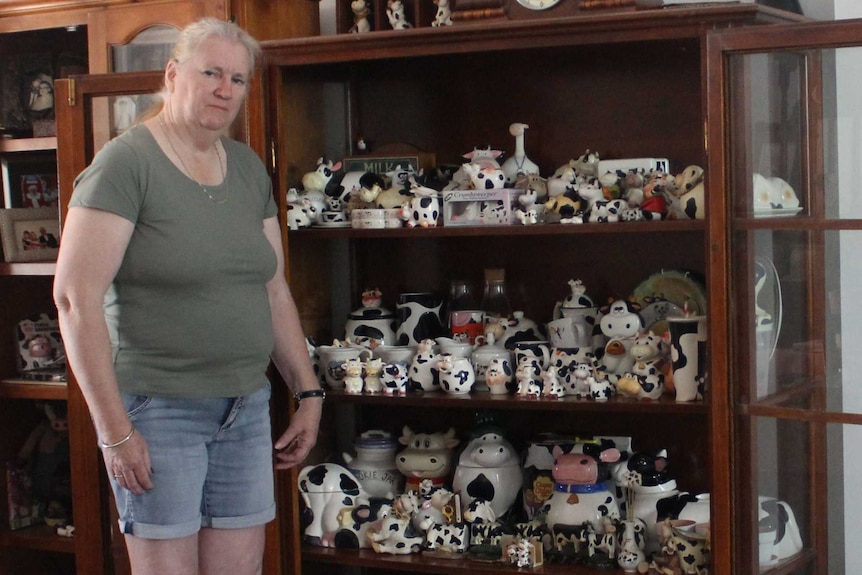 a woman stands in front of a collection of cow ornaments