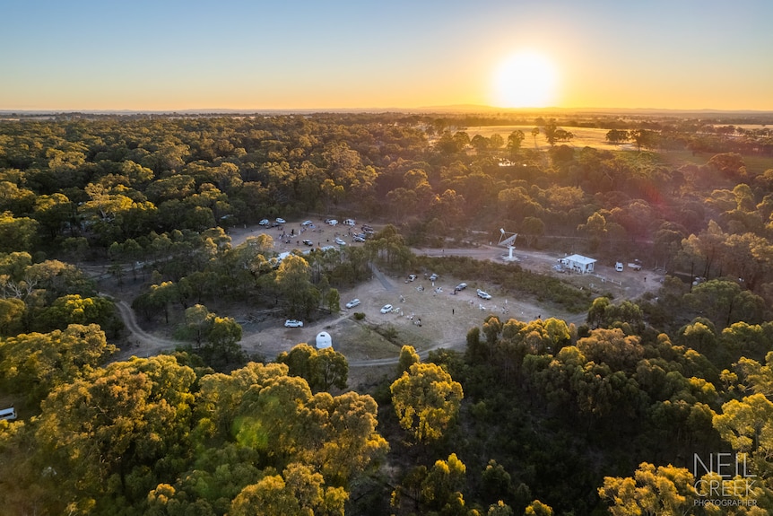 A drone shot of a site surrounded by trees at sunrise or sunset.