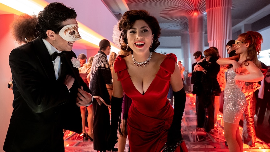 Italian woman with elegantly styled dark hair wears red satin gown, black gloves and diamond necklace at masquerade party