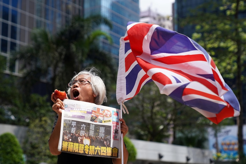 A supporter holds an apple and a copy of Apple Daily newspaper outside the court to support media mogul Jimmy Lai.