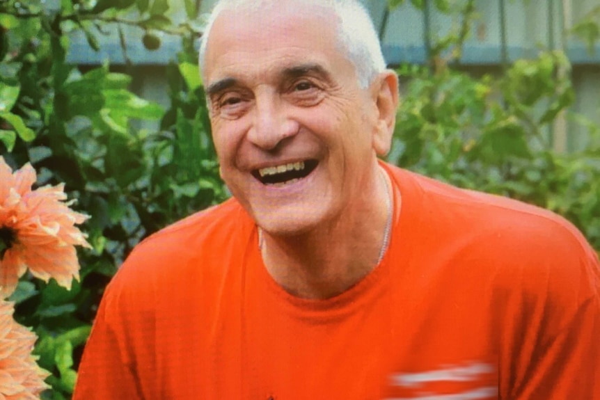 Former Anglican Dean of Newcastle Graeme Lawrence in a garden looking at flowers