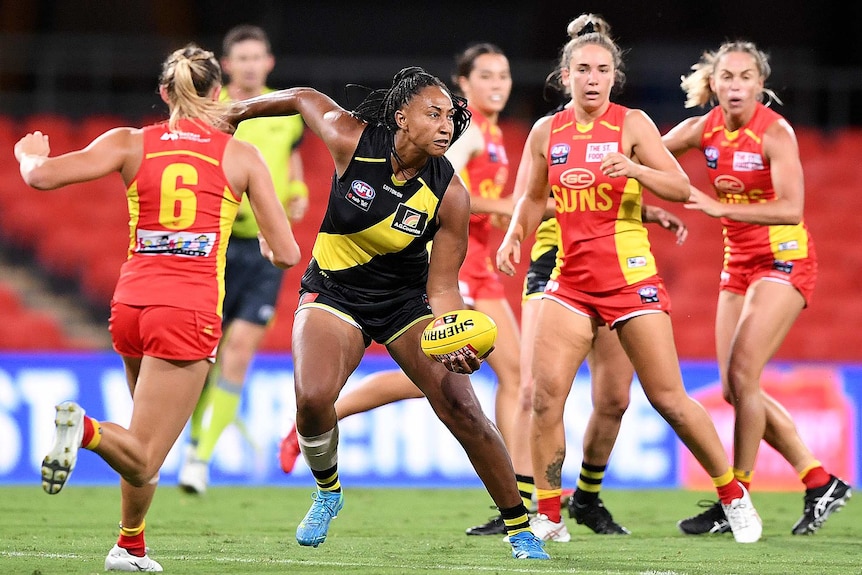 Richmond Tigers AFLW player Sabrina Frederick looks to handpass while surrounded by Gold Coast Suns.