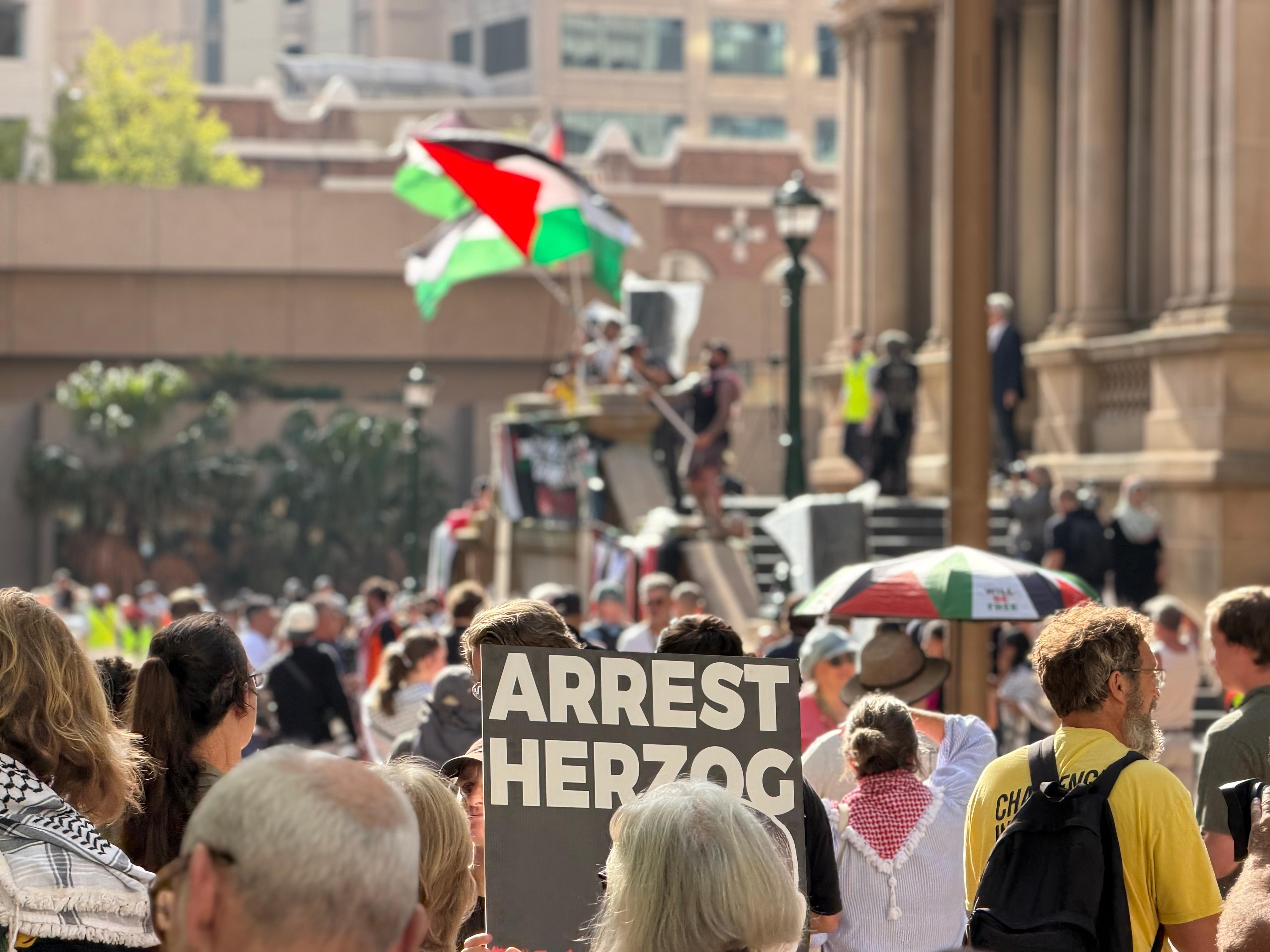 A sign reading 'Arrest Herzog' at the protest in Town Hall
