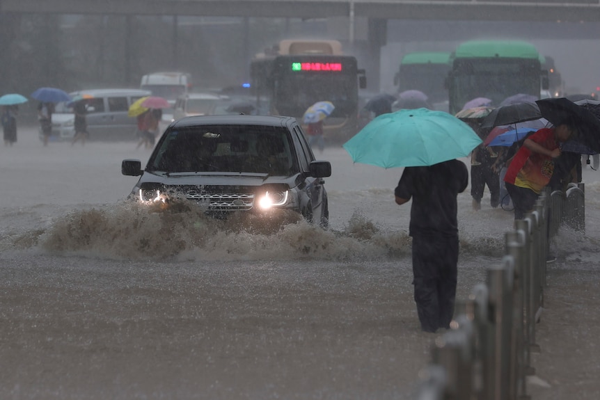 Cars drive through flooded roads