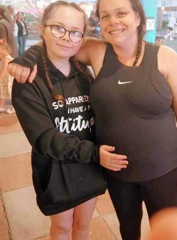 Una niña y una mujer se abrazan y sonríen a la cámara.