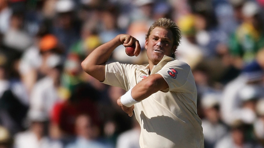 Shane Warne grimaces as he jumps into his delivery stride