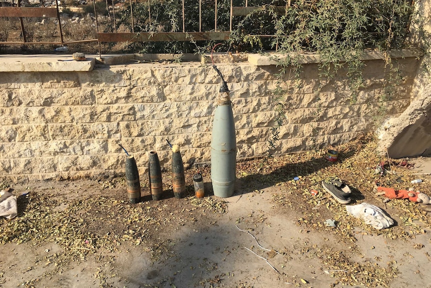 Explosives and bombs lined up against a brick wall.
