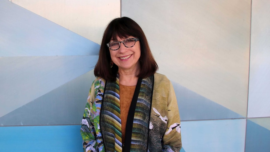 Mid shot of reading and dyslexia expert Dr Maryanne Wolf against a geometric background.