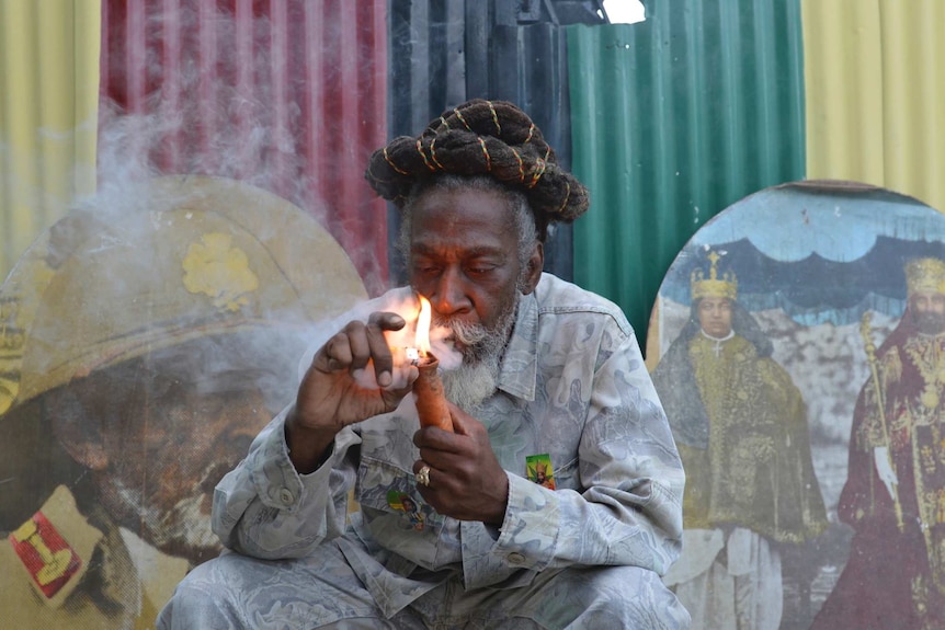 Bunny Wailer smokes a pipe stuffed with marijuana