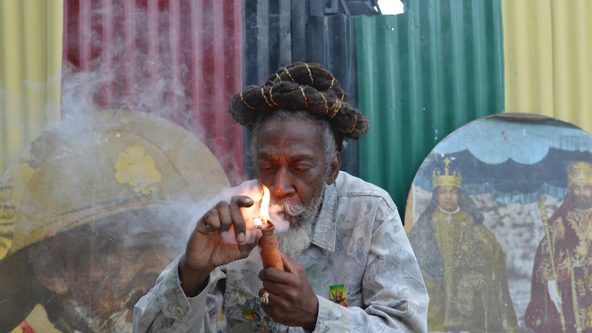 Bunny Wailer smokes a pipe stuffed with marijuana