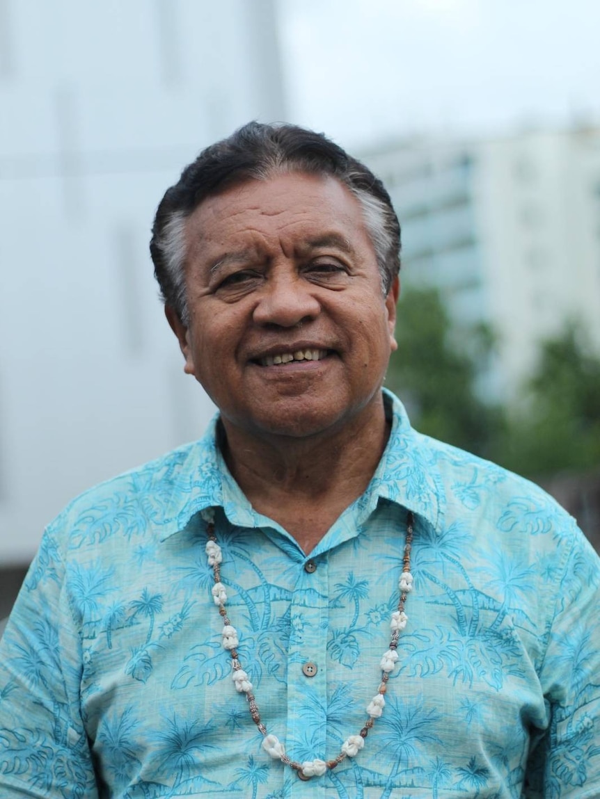 A man with greying hair smiles as he wears a light blue shirt and poses for a headshot.