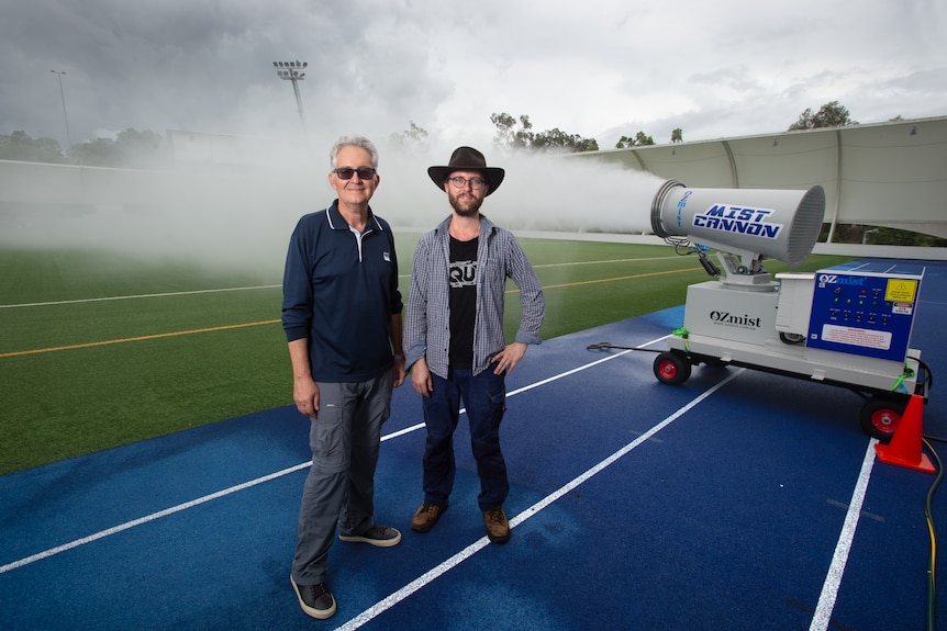 Professor Zoran Ristovski and Dr Joel Alroe stand in front of QUT's mist cannon, which shoots clouds on to an open field