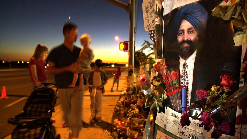 image of smiling sikh man with beard and turban surrounded by flowers and sticky notes on side of the street