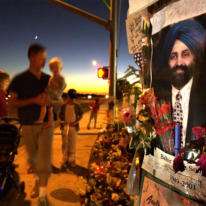 image of smiling sikh man with beard and turban surrounded by flowers and sticky notes on side of the street