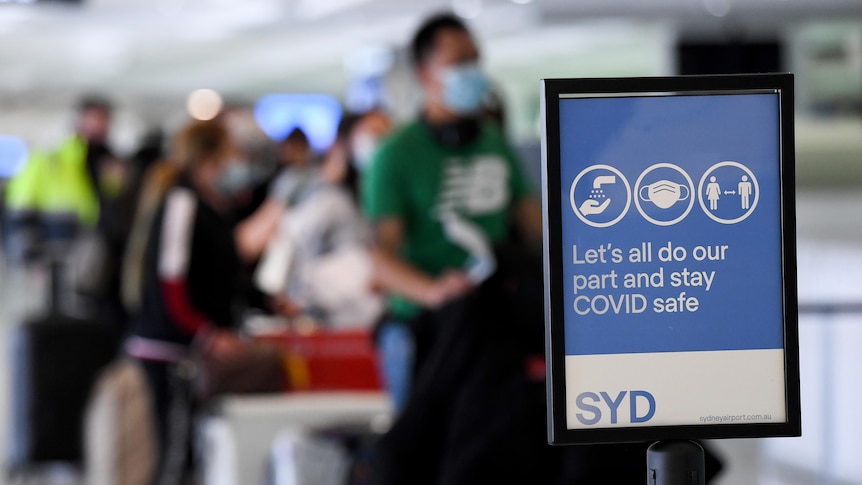 people waiting in line behind a sign at the airport