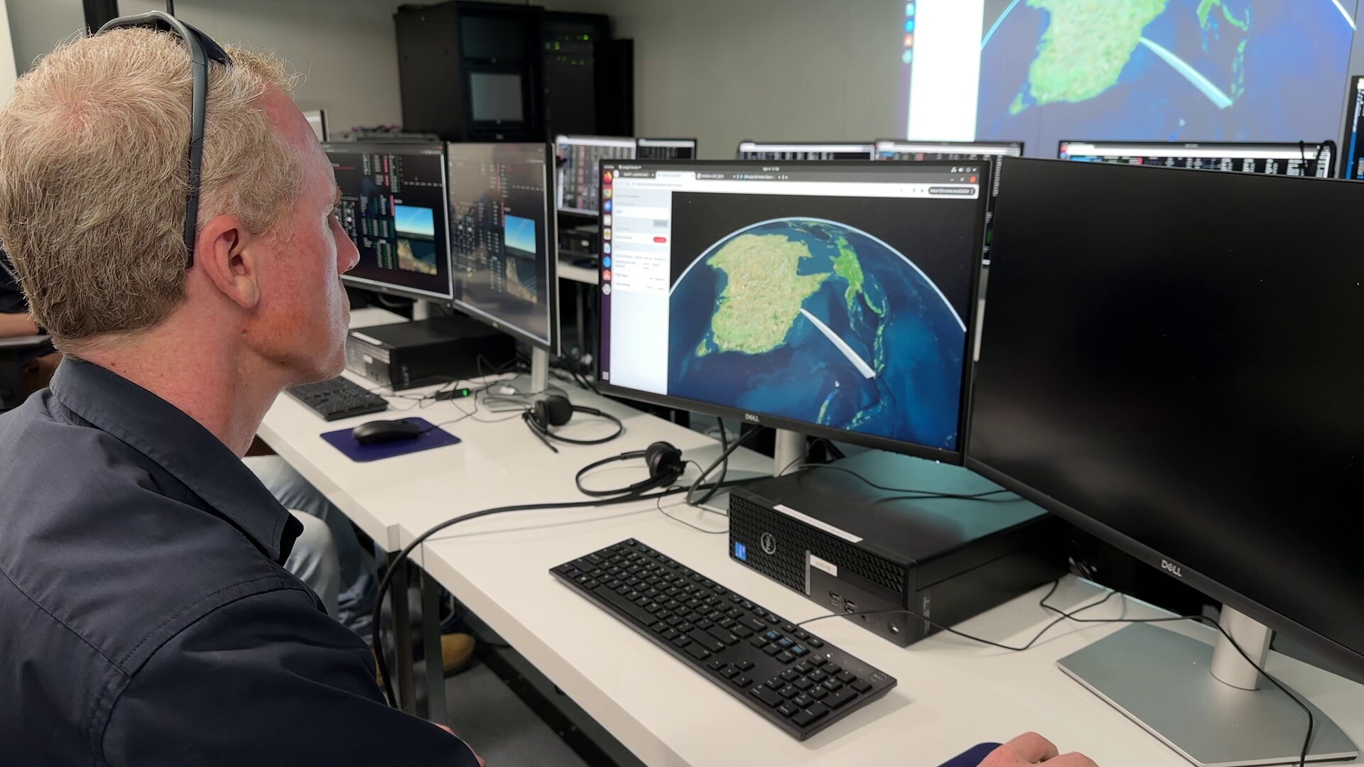 Man sits behind computer and looks at map on screen.