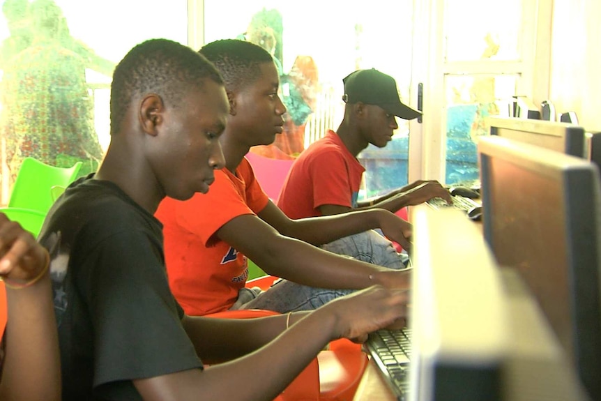 Four young men sit at computers in an internet cafe in Ghana.