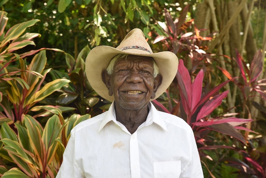 A man wearing a wide-brimmed hat smiles.