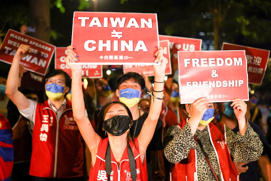 A crowd of demonstrators hold signs saying Taiwan is not China while wearing masks.