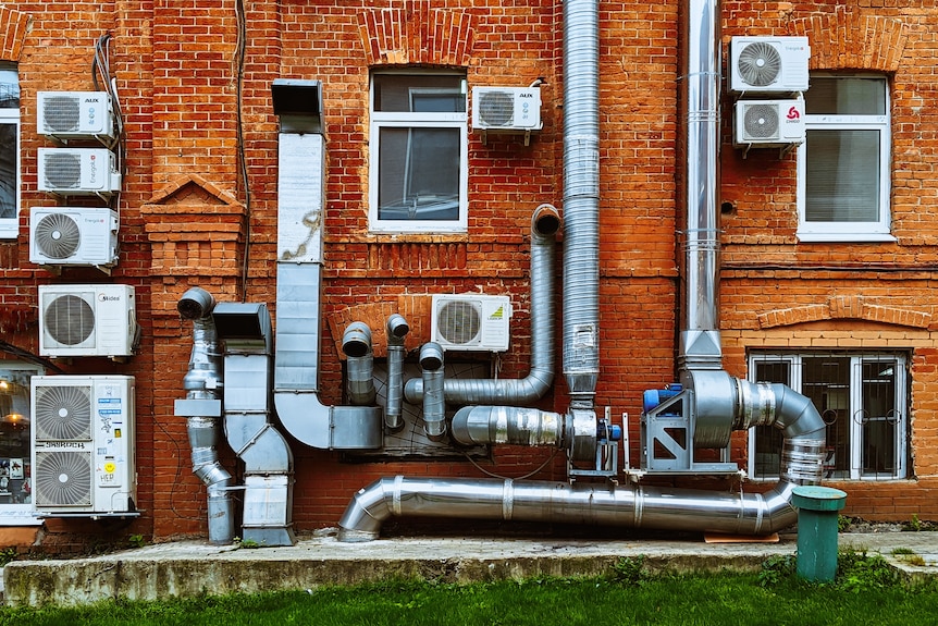 Un edificio con muchas unidades externas de aire acondicionado en la pared