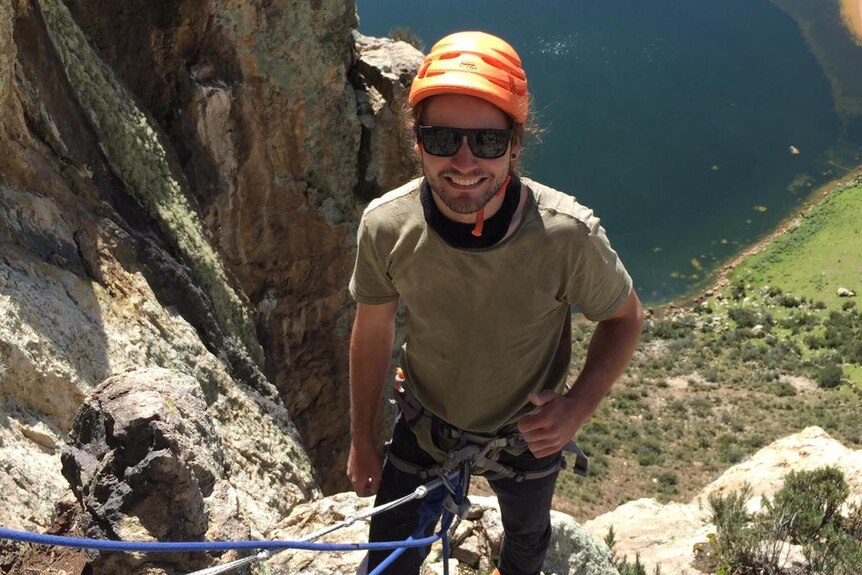 Jarred Spry stands on a ledge with abseiling ropes attached to his harness.