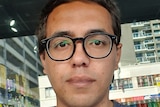A man with black hair and glasses