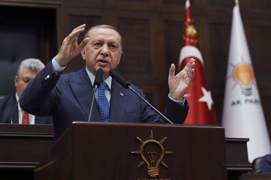 Turkish President Recep Tayyip Erdogan giving a speech from a pedestrial.