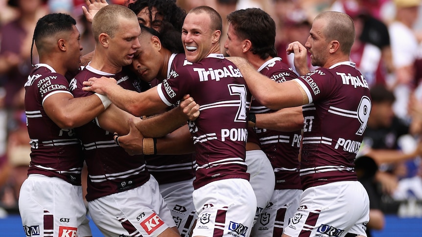 A group of rugby league players celebrate scoring a try