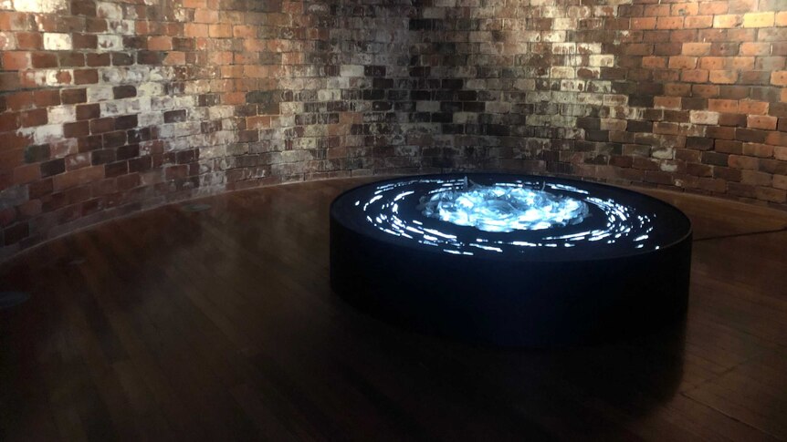 Cast glass displayed on a round, black table. The glass appears to glow as though lit from within.