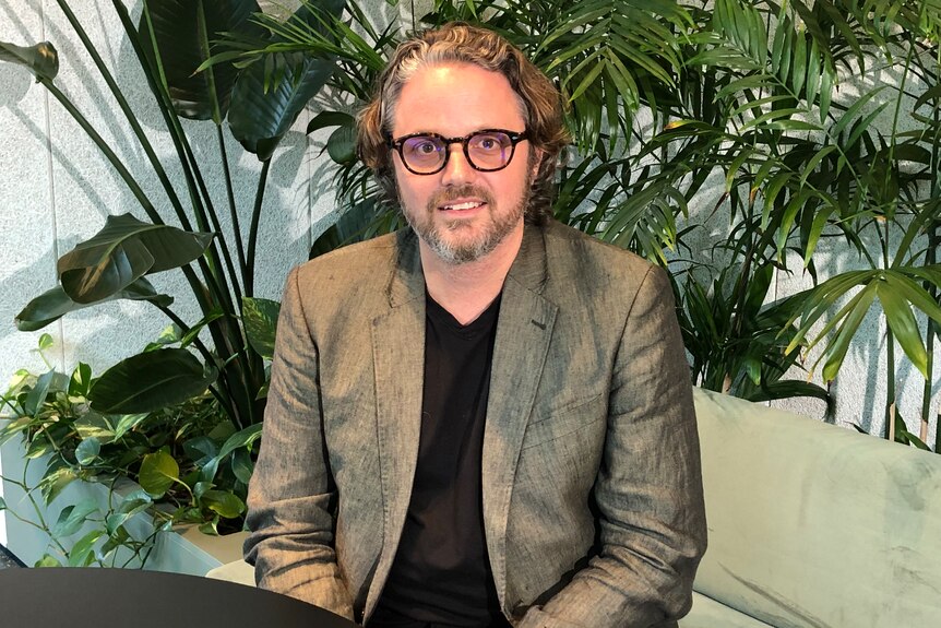 Jeff in a suit jacket and t-shirt with glasses.