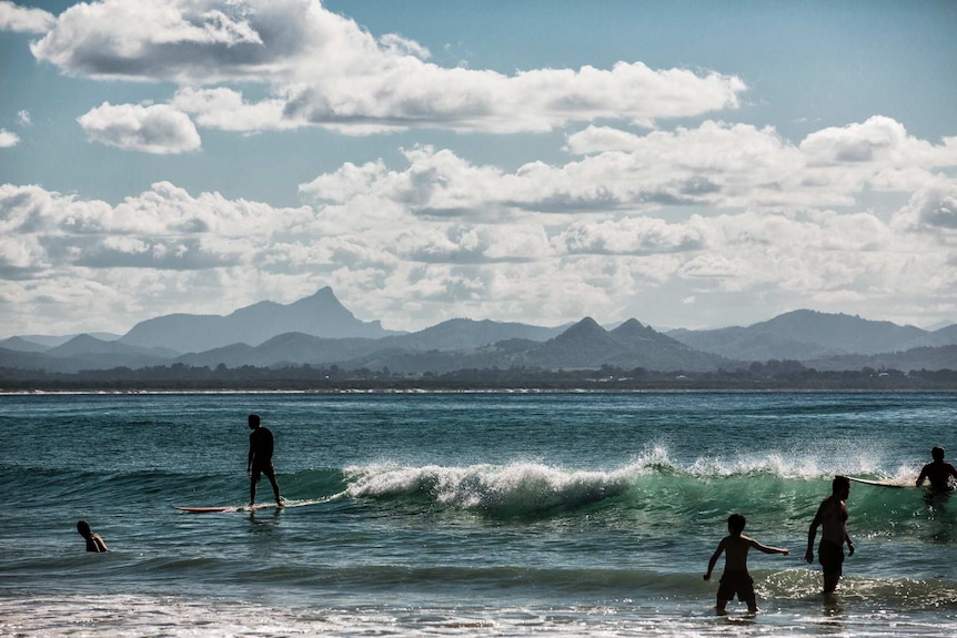 A landscape photo of a man surfing in front of mountains