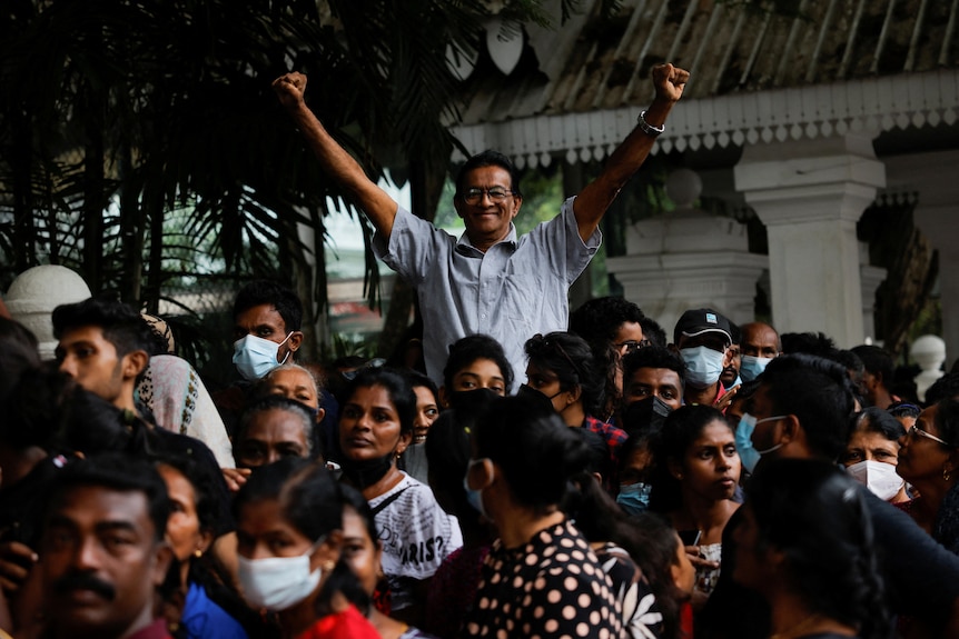 Man waves his fists up in the air in victory sign above a crowd of people.