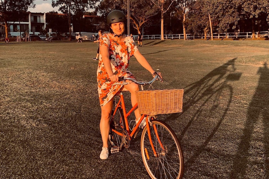 A woman sits on her bike in the middle of a park.