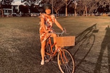 A woman sits on her bike in the middle of a park.