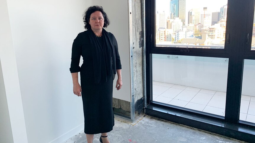 Unit owner Louisa Carter stands near a window with city views in her unfinished Spring Hill apartment.