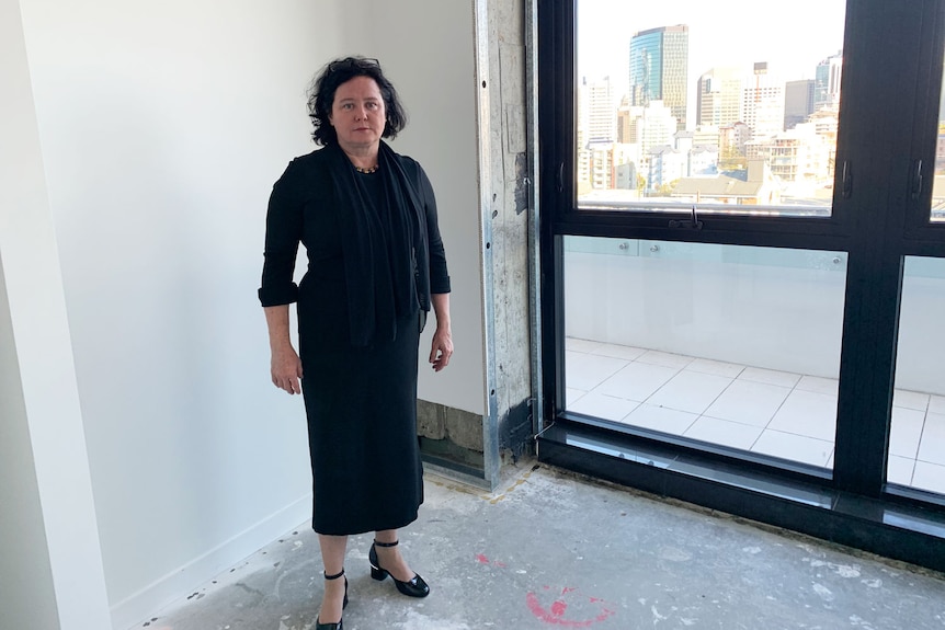 Unit owner Louisa Carter stands near a window with city views in her unfinished Spring Hill apartment.