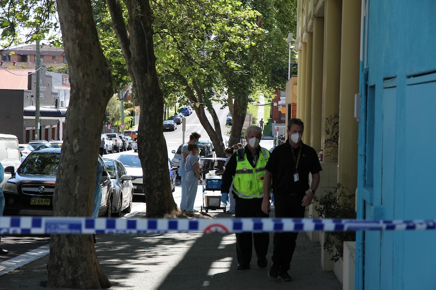 Two men walking down a street behind a police tape.