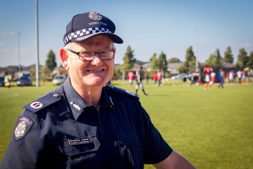 Victoria Police Assistant Commissioner Stephen Leane stands at a football field, wearing uniform and smiling.