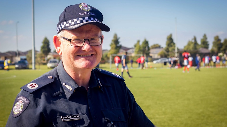 Victoria Police Assistant Commissioner Stephen Leane stands at a football field, wearing uniform and smiling.