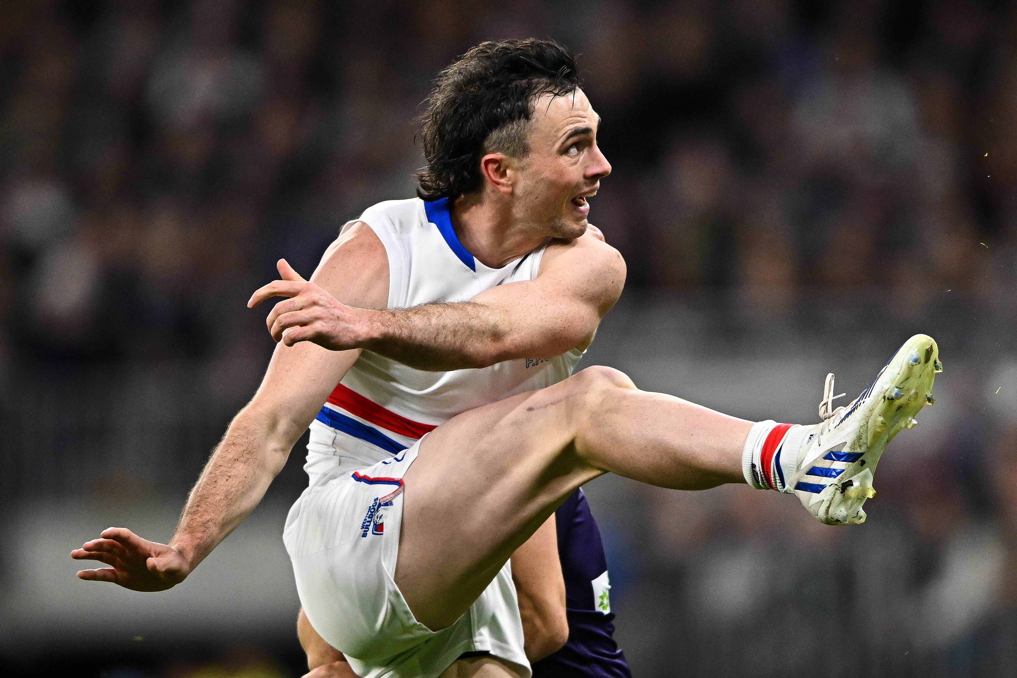 A Western Bulldogs AFL player kicks the ball against the Dockers.