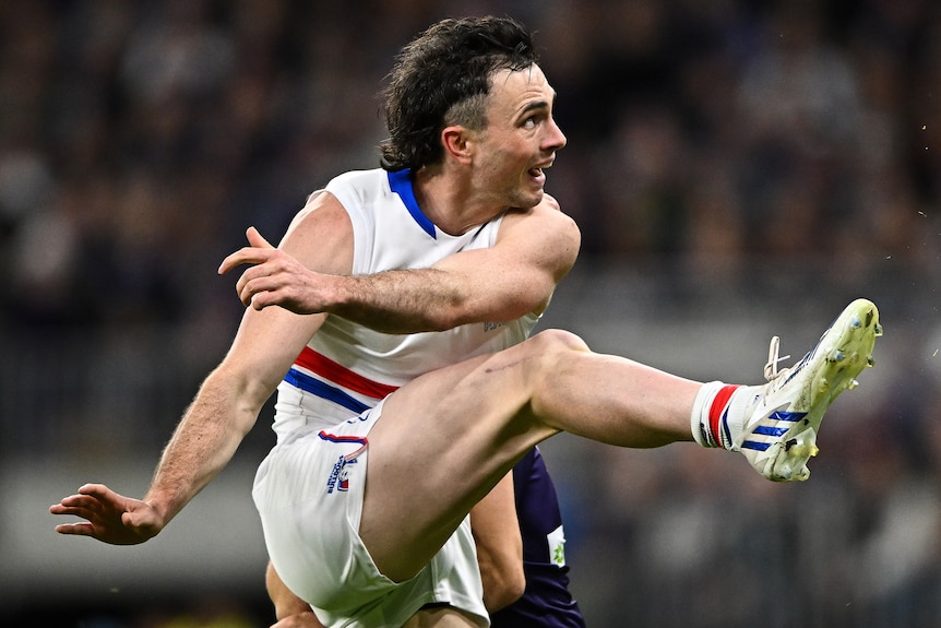 A Western Bulldogs AFL player kicks the ball against the Dockers.