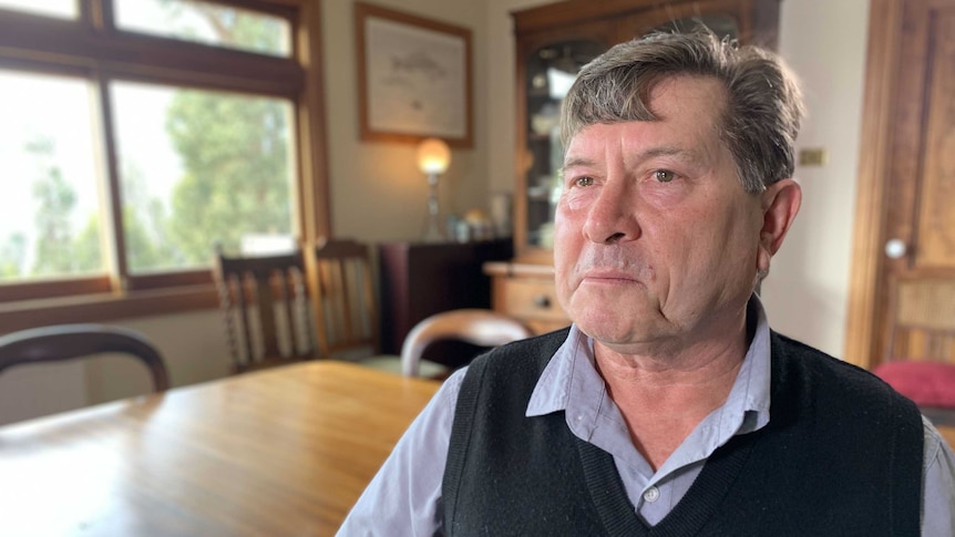 Michael King, who survived the Dunalley bushfires, sits in his living room