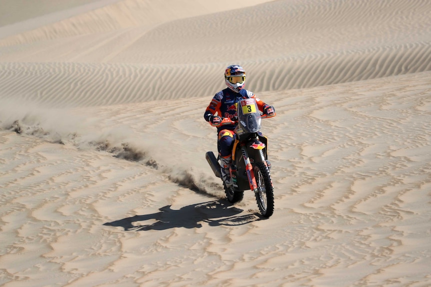A man rides a motorbike on sand