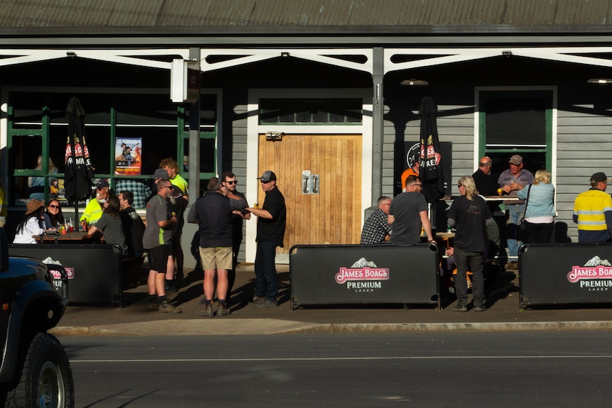 An after work crowd enjoying afternoon sun outside a bush Pub